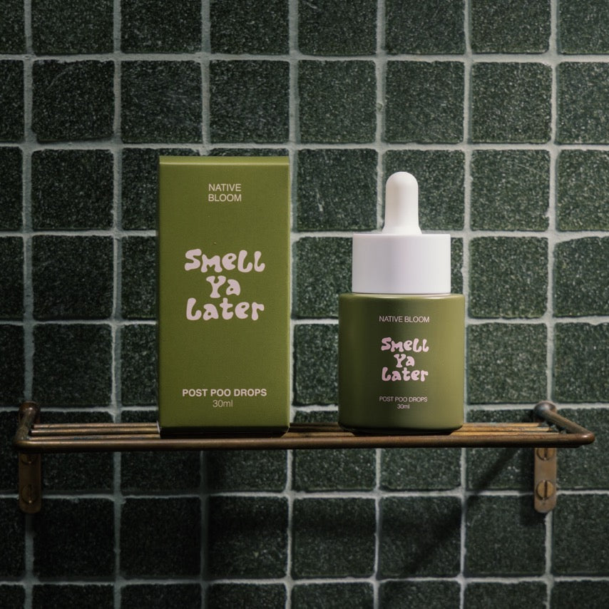 Green bottle and box labeled 'Smell Ya Later' on a wooden shelf against a green tiled wall.